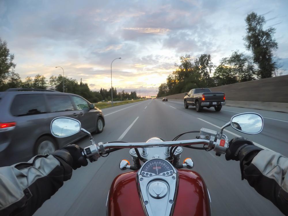 point of view of helmet while person rides a motorcycle on the highway during a vibrant sunset